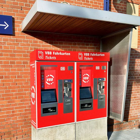 Zwei rot beklebte VBB-Fahrausweisautomaten am Bahnhof.