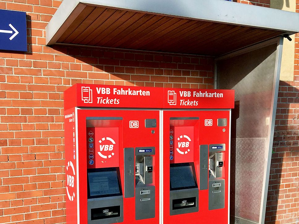 Zwei rot beklebte VBB-Fahrausweisautomaten am Bahnhof.