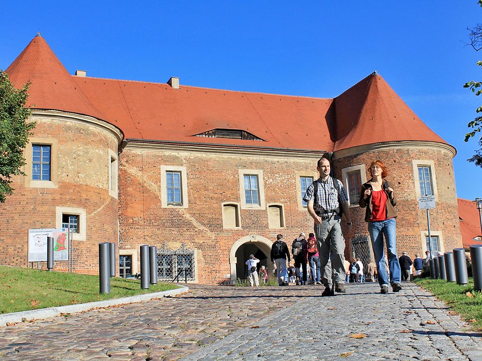 Blick auf die Burg Eisenhardt in Bad Belzig, davor Wanderer.