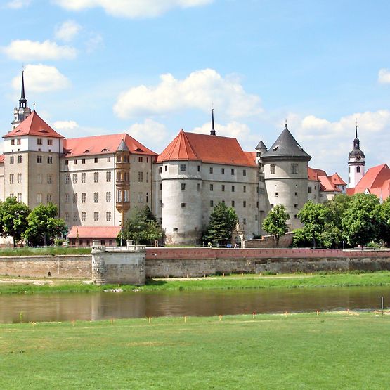 Außenaufnahme von Schloss Hartenfels in Torgau, im Vorderrund Wasser.