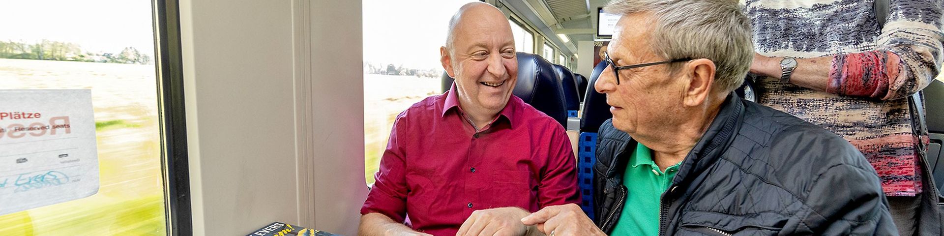 Autor Horst Evers sitzt im Zug, neben im Fans. Er signiert seine Bücher.