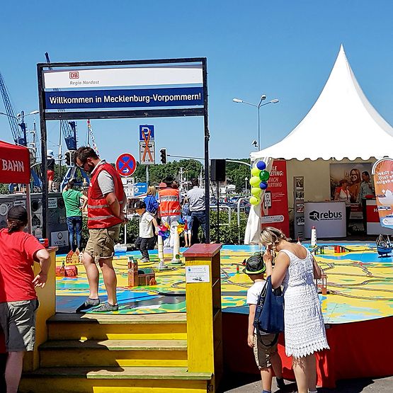 Stand von DB Regio Nordost beim MV-Tag 2018, bunte Spielfläche und Menschen.