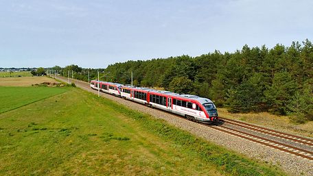Kulturzug auf der Strecke fährt durch grüne Landschaft.