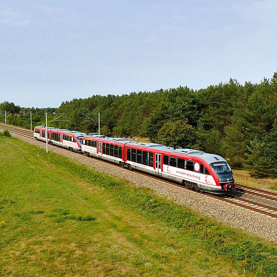 Kulturzug auf der Strecke fährt durch grüne Landschaft.