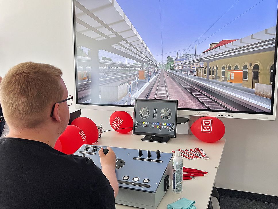 Ein Mann ist von hinten zu sehen, er steuert am Simulator einenvirtuellen Zug.