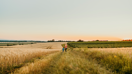 Eine Mutter steht mit ihrem Sohn in einem Feld. Im Hintergrund sieht msn einen Zug.