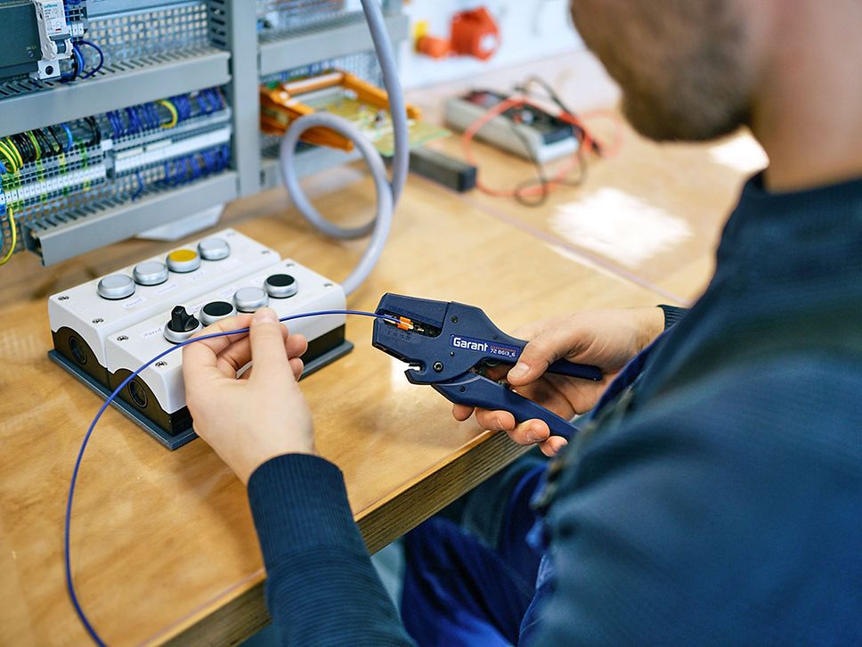 Detailaufnahme, ein Mann arbeitet mit einer Zange an einem Kabel.