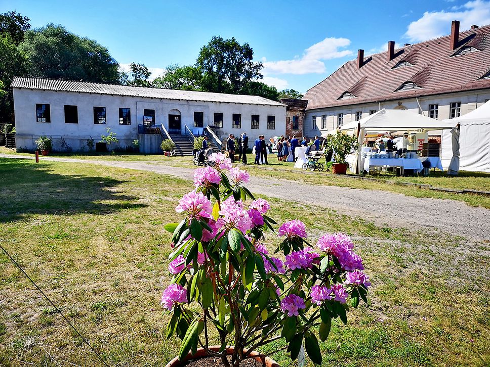 Totale mit Blick auf das Schlossgut Schönwalde, im Hintergrund ein Gehöfft, Menschen feiern.