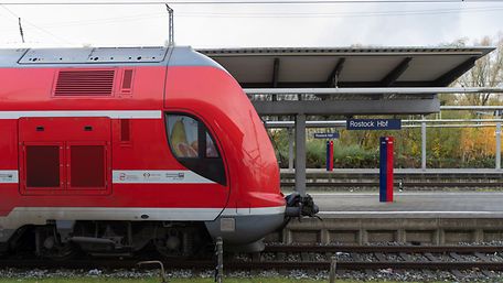 Ein roter Regionalzug steht am Bahnhof Rostock.