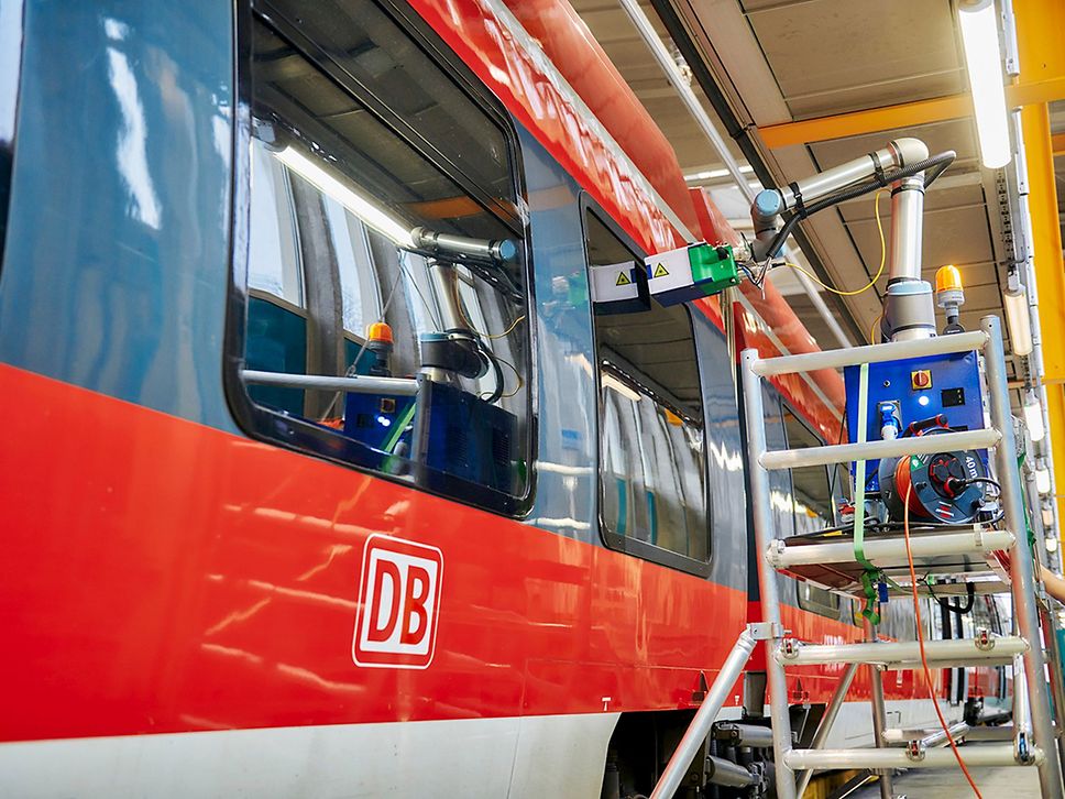Laser auf einem Gerüst am Fenster eines roten Regionalzuges.