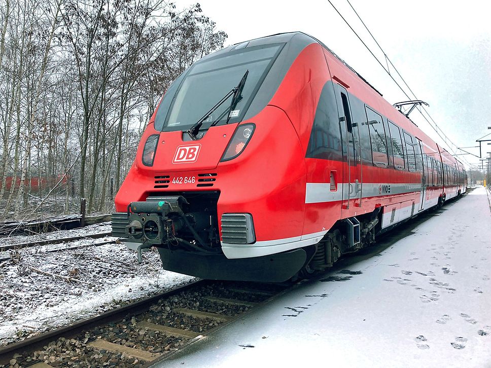 Roter Regionalzug steht auf der Schiene, es liegt etwas Schnee.
