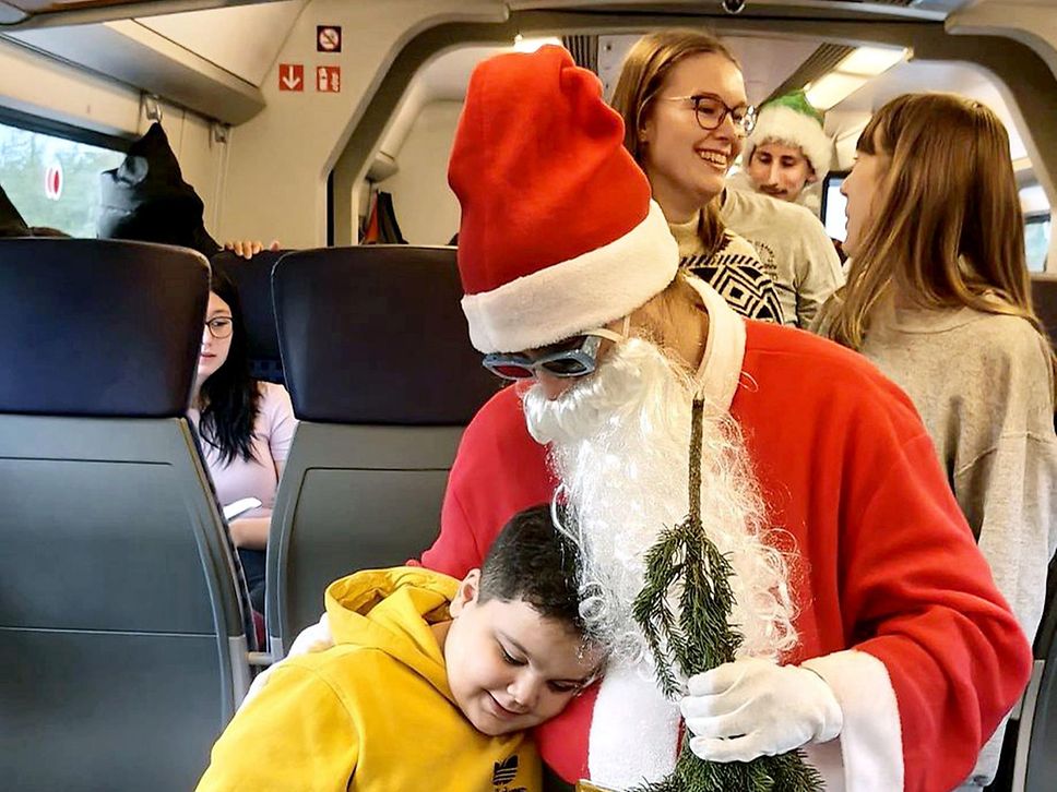 Ein Junge im gelben Pullover umarmt den Nikolaus.