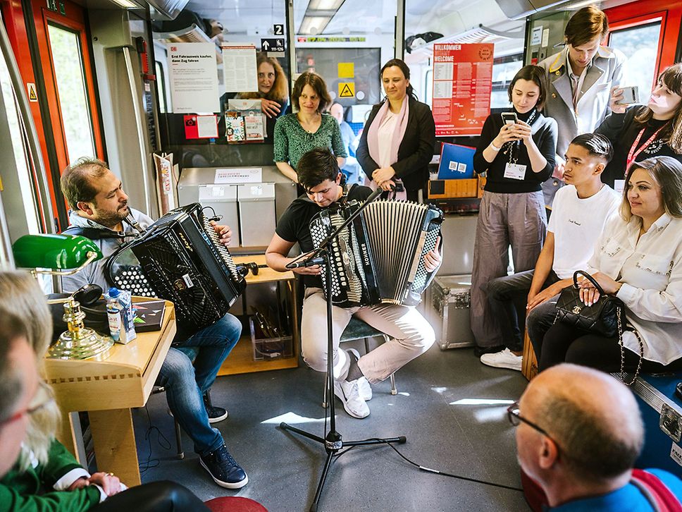 Konzert im Kulturzug, zwei Männer spielen Akkordeon in der Mitte des Publikums.