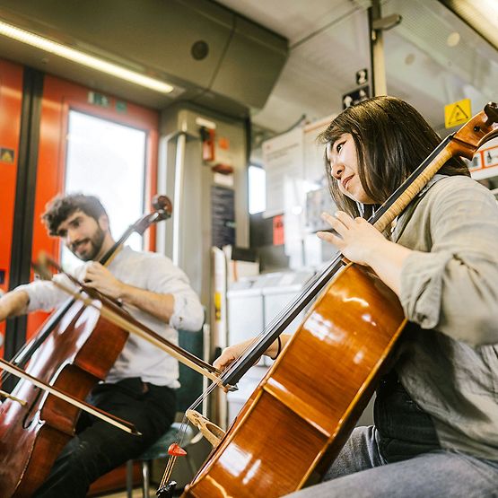 Ein Mann und eine Frau spielen Cello in einem Regionalzug.