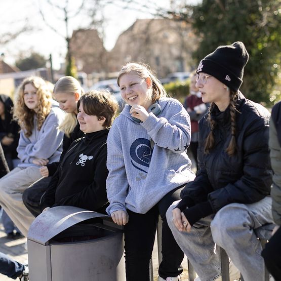 Schüler:innen in einer Reihe, sie sprechen mit jemandem, der nicht zu sehen ist.