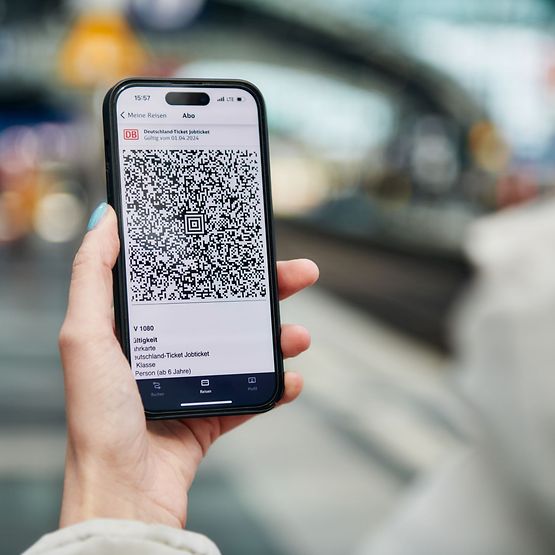 Blick über die Schulter einer Person, die ein Smartphone in der Hand hält. Ein digitales Ticket ist geöffnet.