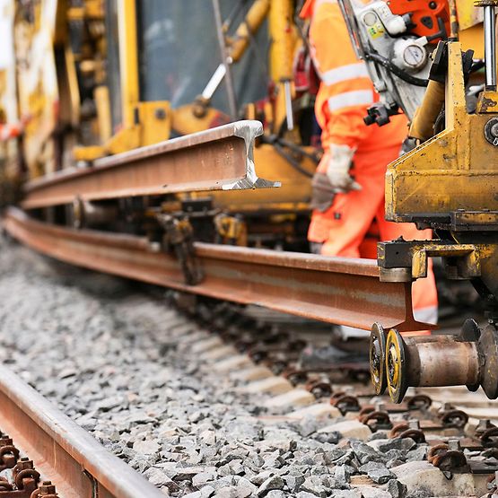 Eine Baumaschine tauscht alte Gleise gegen neue aus.
