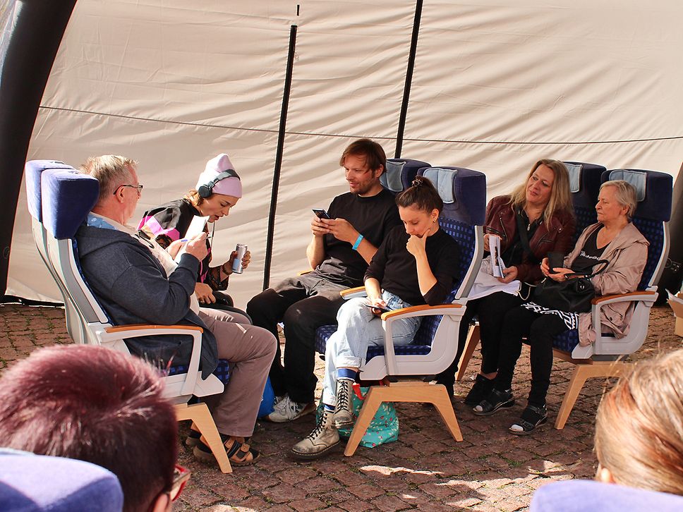 Schauspielende und Publikum simulieren beim Workshop eine Zugfahrt.