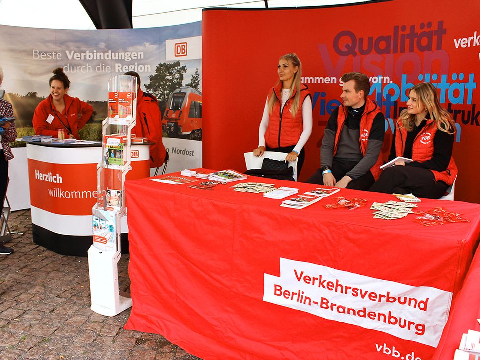 Mitarbeitende stehen an den Infoständen von DB Regio Nordost und VBB für Gespräche bereit und verteilen Infomaterial.