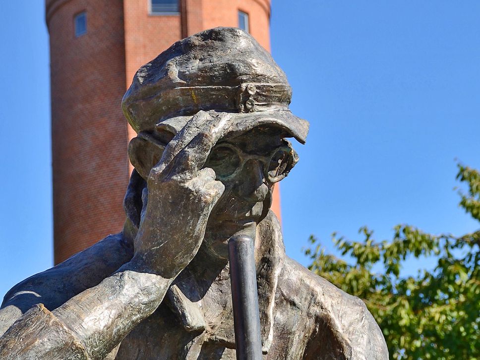 Nahaufnahme der Bronzefigur mit dem Titel Straßenfeger.