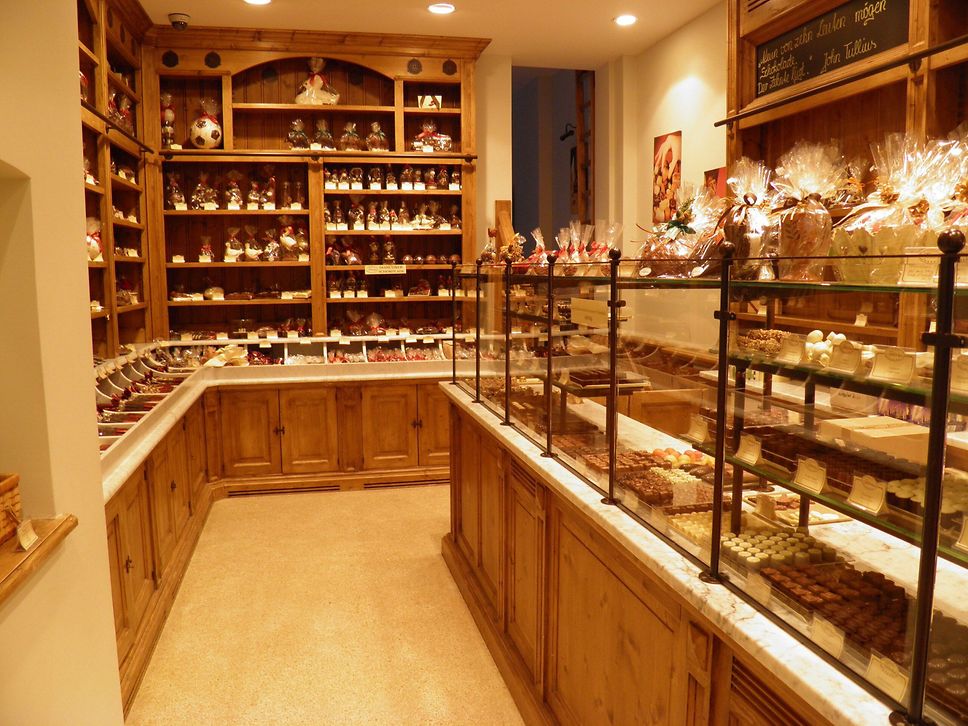 Blick in einen Verkaufsraum mit Regalen und Vitrinen, in denen Schokolade liegt.