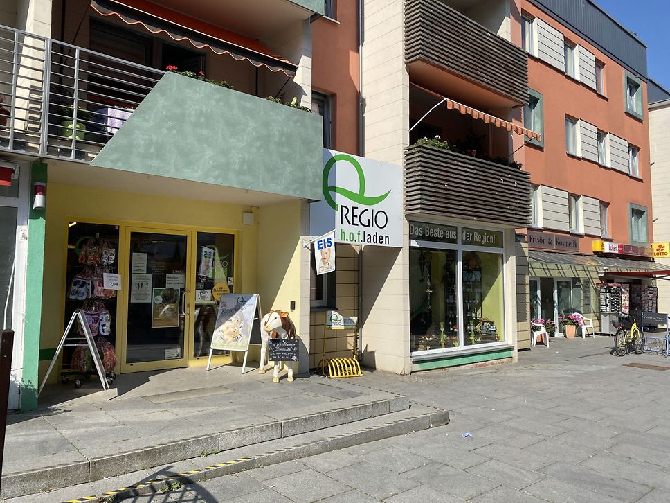 Blick in eine Einkaufsstraße mit Eingang zum Q-Regio Hofladen.