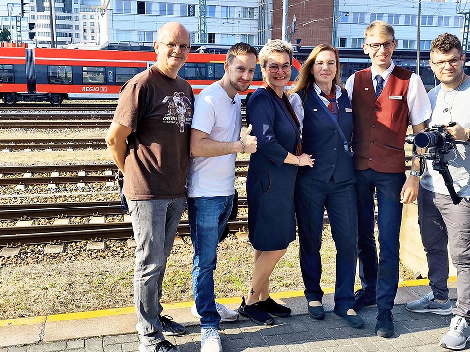 Gruppenfoto mit vier Männern und zwei Frauen, ein Mann hält eine Kamera.