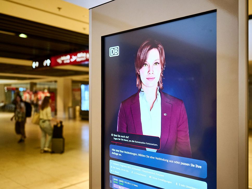Foto eines digitalen Terminals, darauf zu sehen ist der Avatar einer Frau in DB-Kleidung.