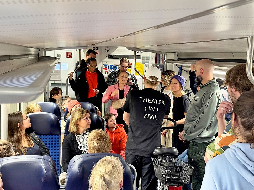 Menschen stehen und sitzen in einem Zug, sie unterhalten sich.