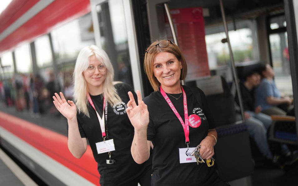 Zwei Mitarbeiterinnen winken aus der Tür des Kulturzugs