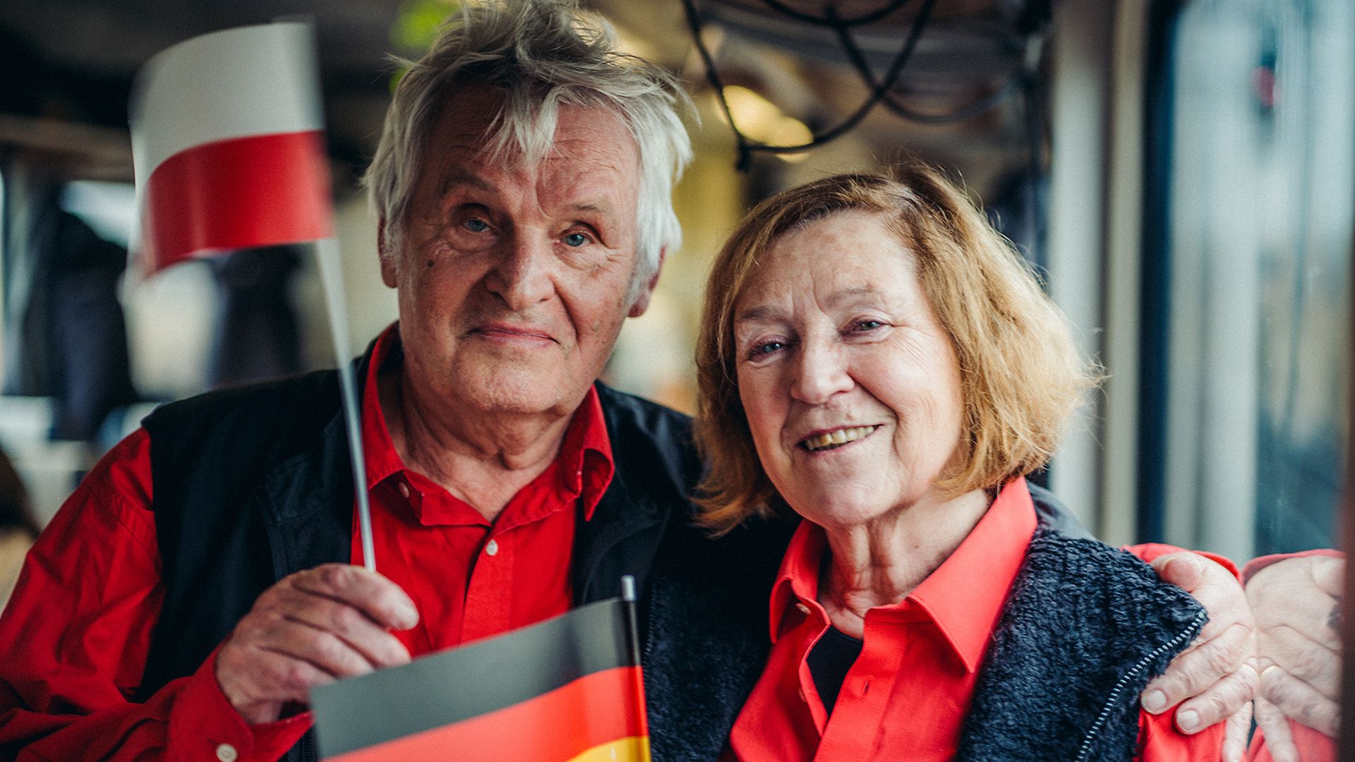 Ein Mann schwenkt eine polnische, eine Frau eine deutsche Flagge im Kulturzug