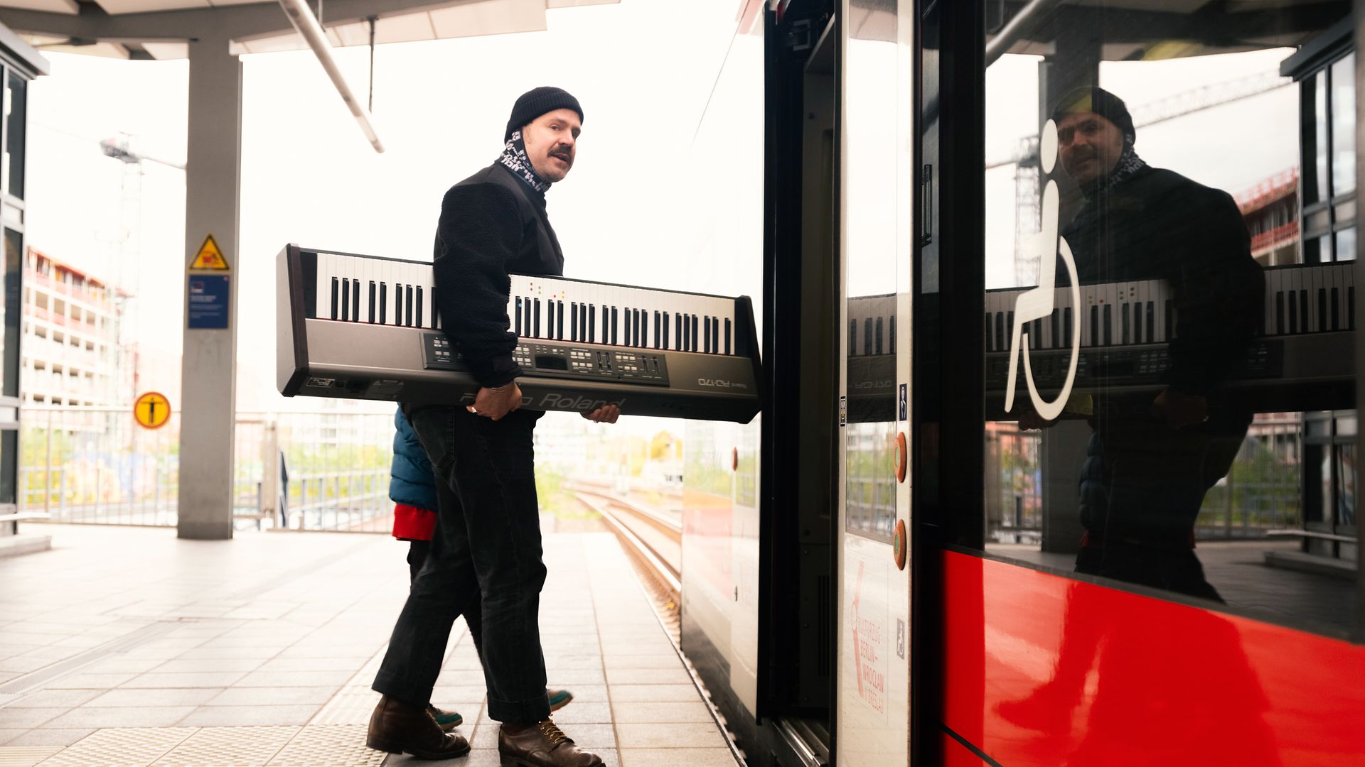 Ein Mann trägt ein großes Keyboard in den Kulturzug
