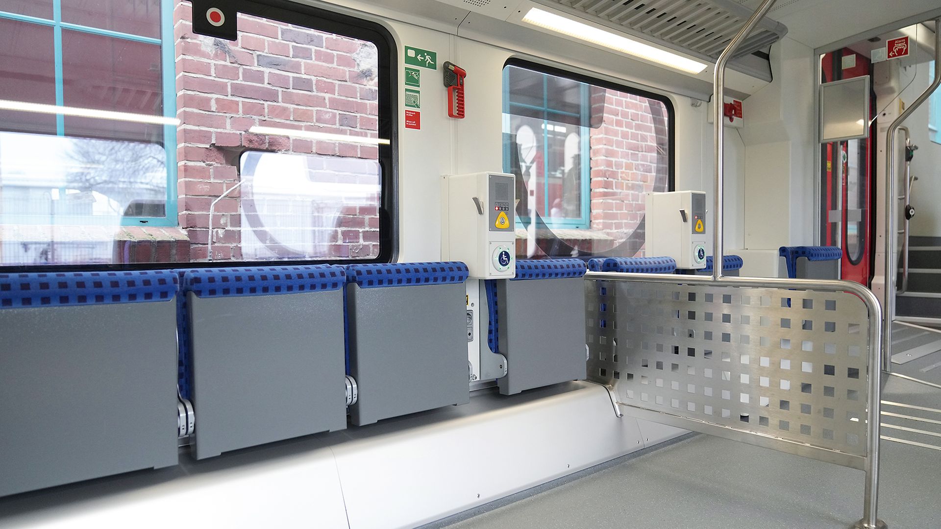 Klappstize und Rollstuhlplatz mit einer metallenen Anlehnstange für mehr Sicherheit im Dosto