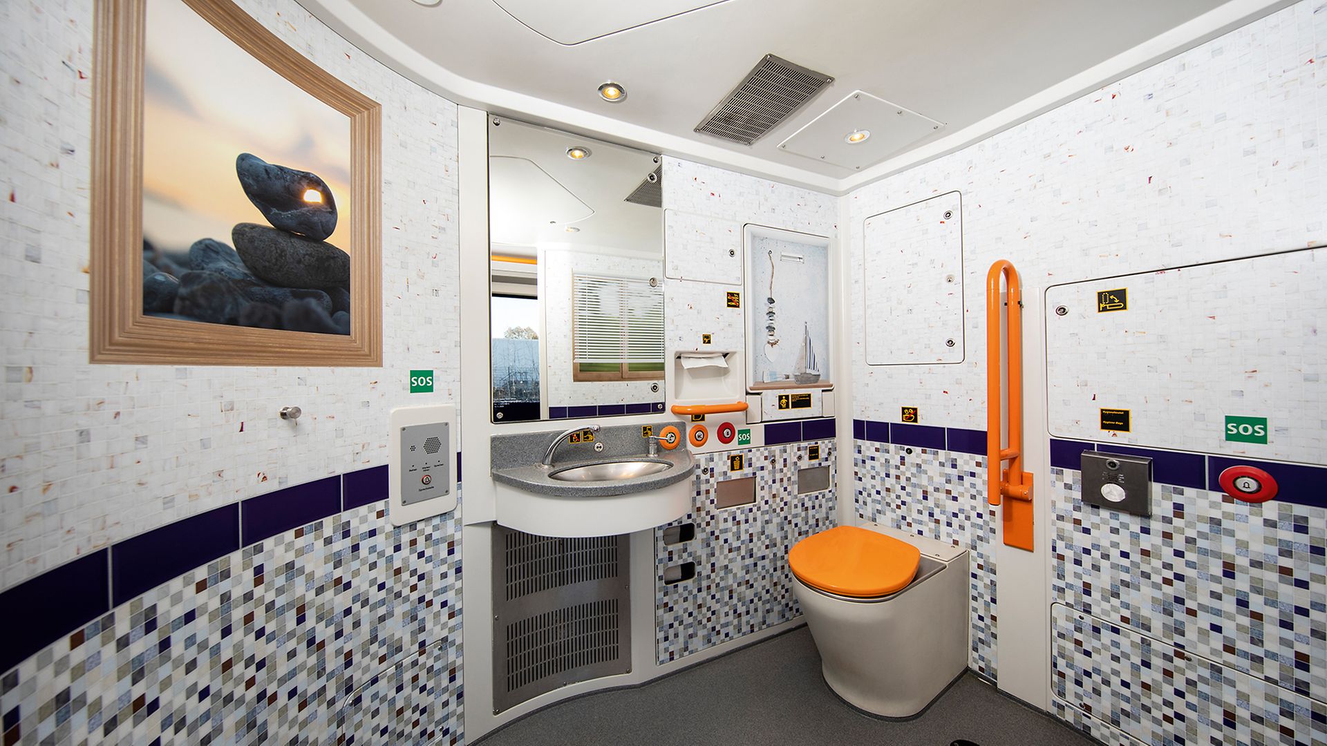 Motivfolien mit aufgdruckten Kacheln und eine, gerahmten Bild im Universal-WC im Talen-2-Fahrzeug