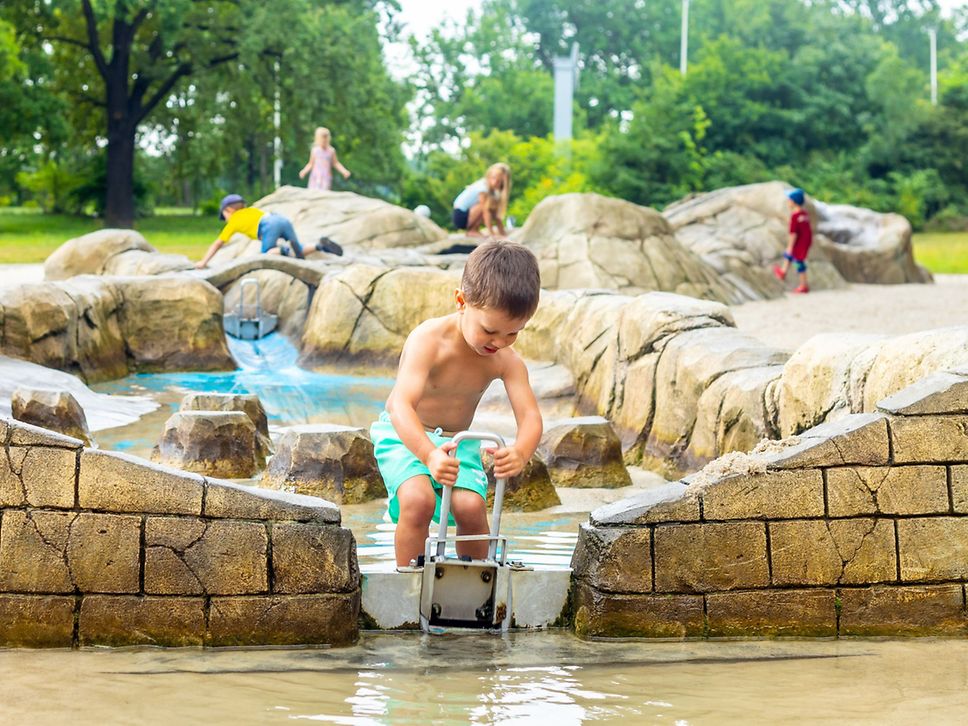 Ein Junge spielt auf einem Wasserspielplatz.
