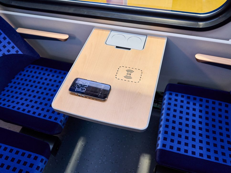 Auf einem Tisch des neuen Fahrzeugs liegt ein Smartphone und wird über Induktion geladen.