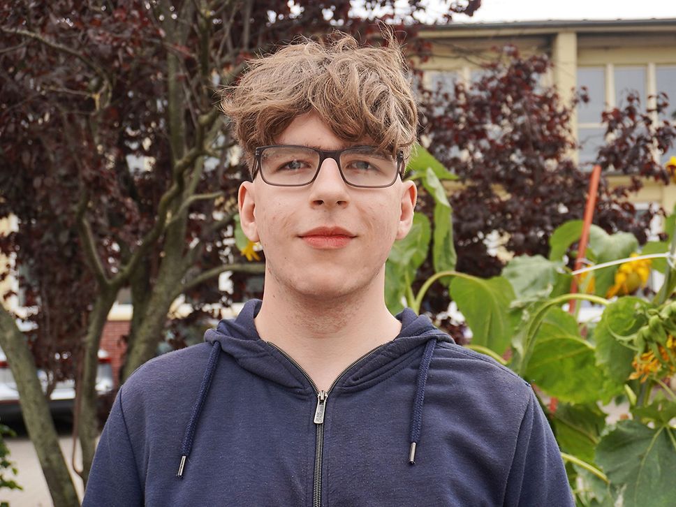 Porträt eines 16-Jährigen Jungen, er trägt Brille, kurze braune Haare und eine blaue Sweatjacke.