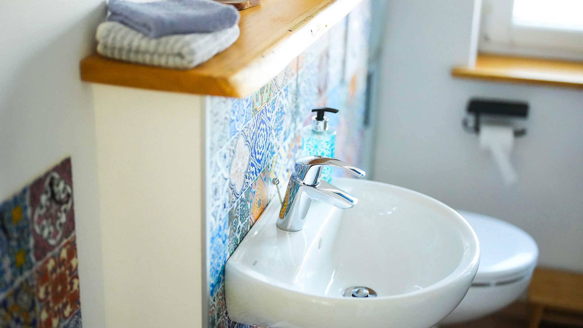 Weißes Waschbecken mit bunten Kacheln im Hintergrund