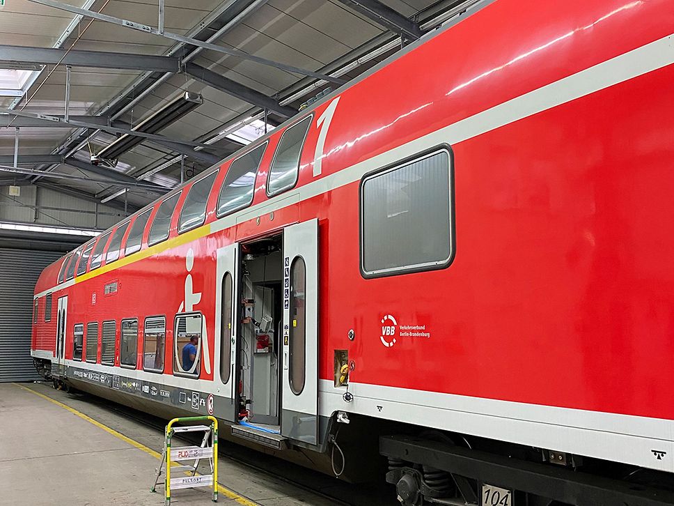 Roter Doppelstockzug in einer Halle, eine Tür steht offen, davor eine kleine Leiter.