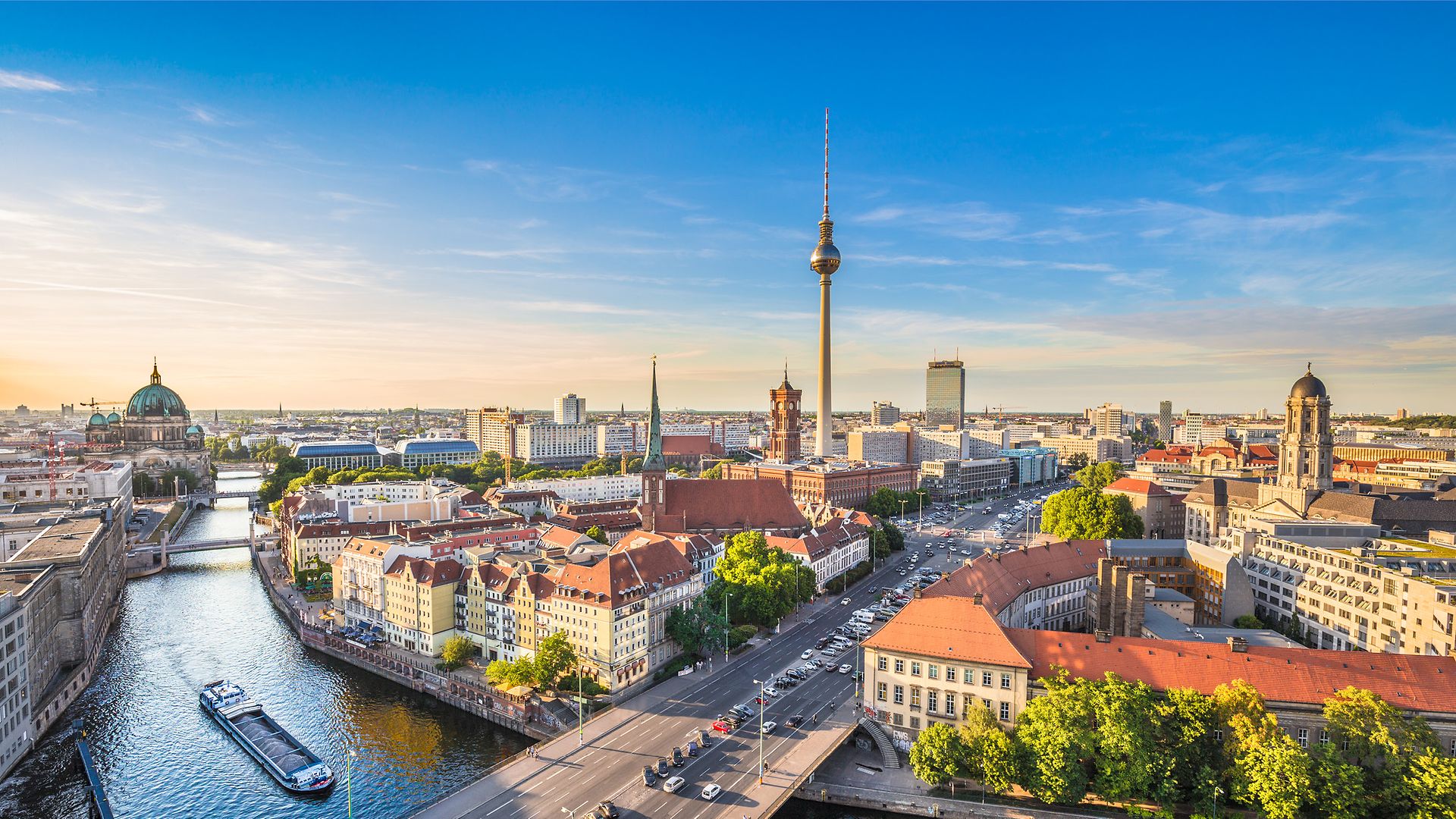 Das Bild zeigt Berlin aus der Luftperspektive bei strahlend blauem Himmel. Im Hintergrund sieht man den Fernsehturm.