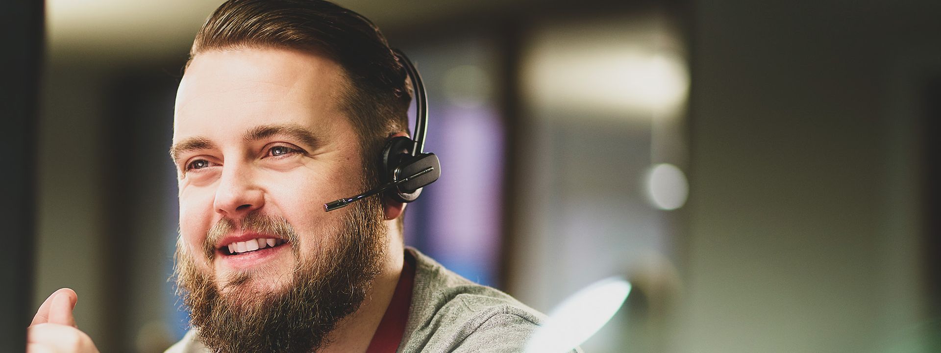 Quelle: istock.com / sturti Junger Mann mit Vollbart berät Kunden am Telefon. Er trägt ein Headset.