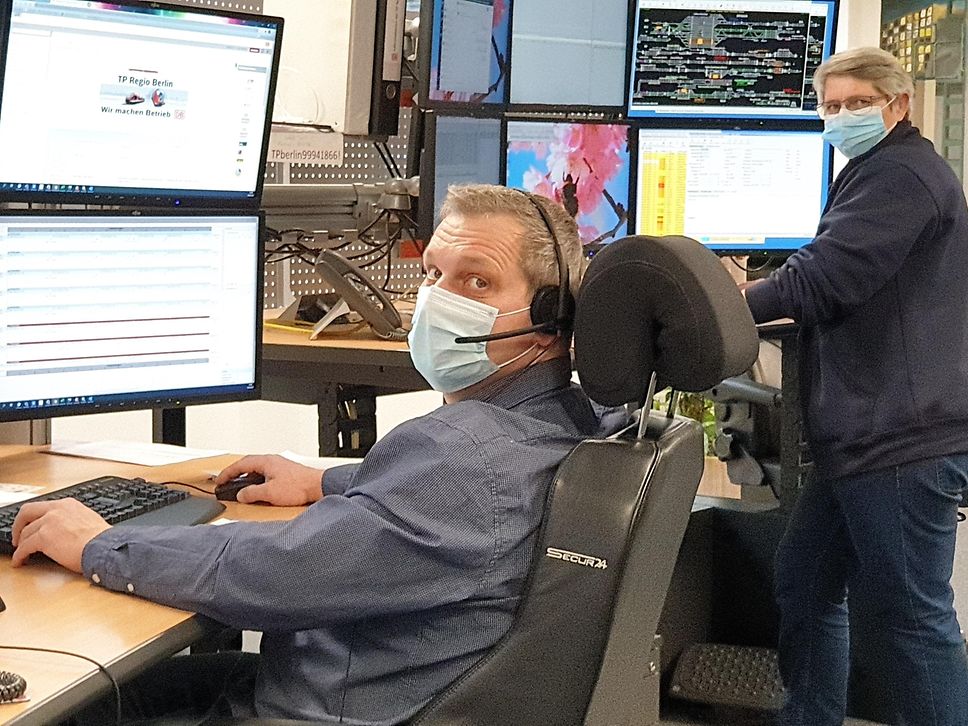 Eine Mitarbeiterin und ein Mitarbeiter sitzen in der Leitstelle+ vor jeweils 6 Monitoren.