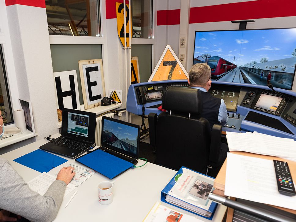 Hinter dem Lokführer am Simulator steuert der Trainer die zu übenden Aufgaben über zwei Laptops