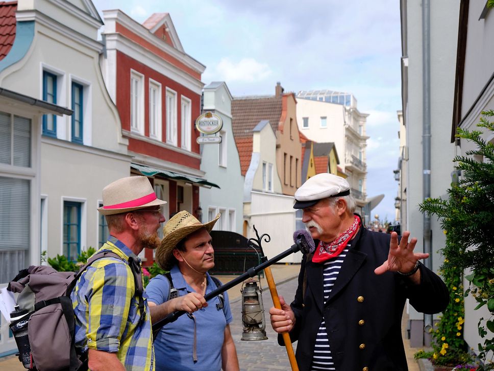 Drei Männer unterhalten sich in einer alten Gasse.