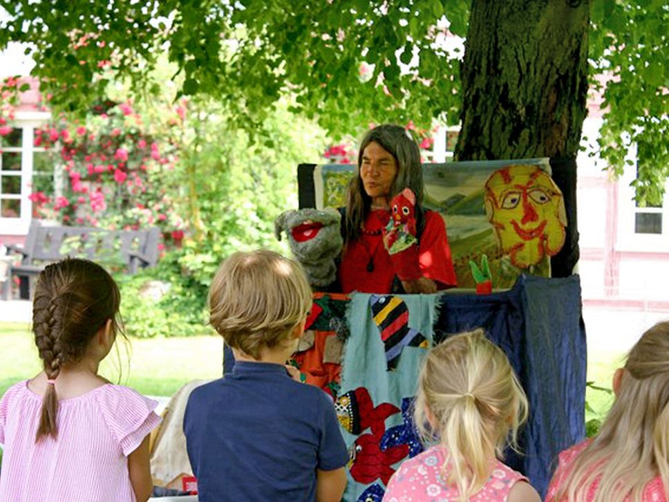 Eine Puppenspielerin spielt vor einer Gruppe Kinder.