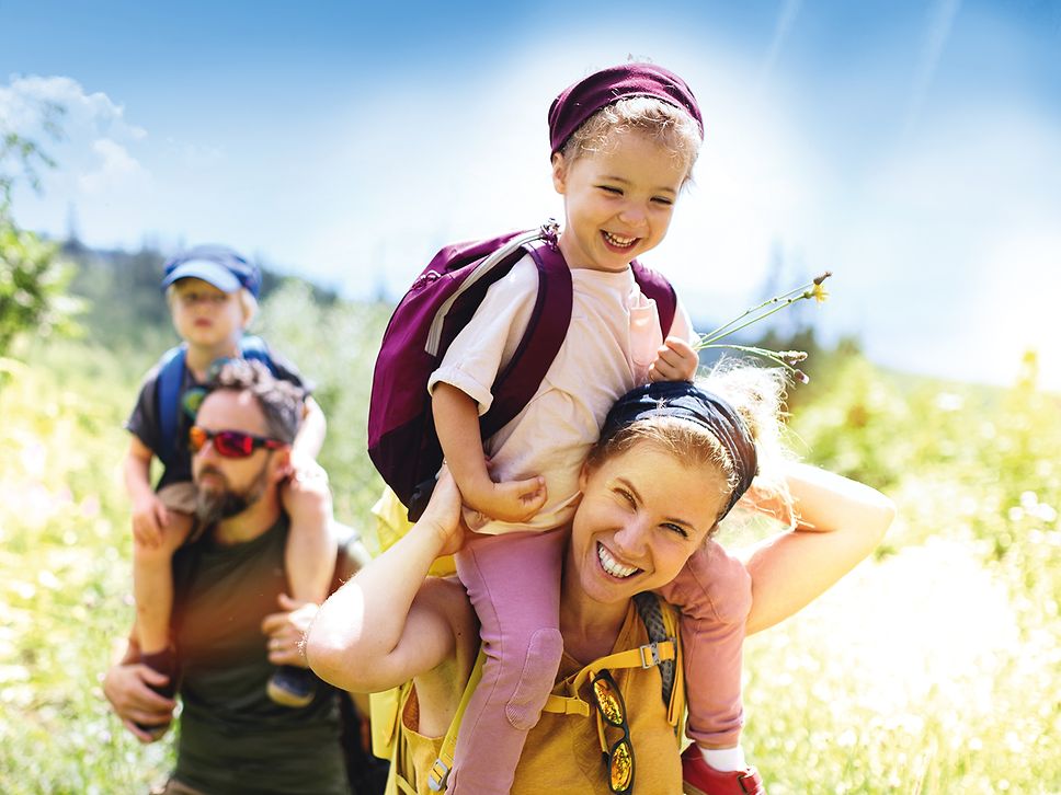 Eine Familie ist unterwegs und lächelt in die Kamera.