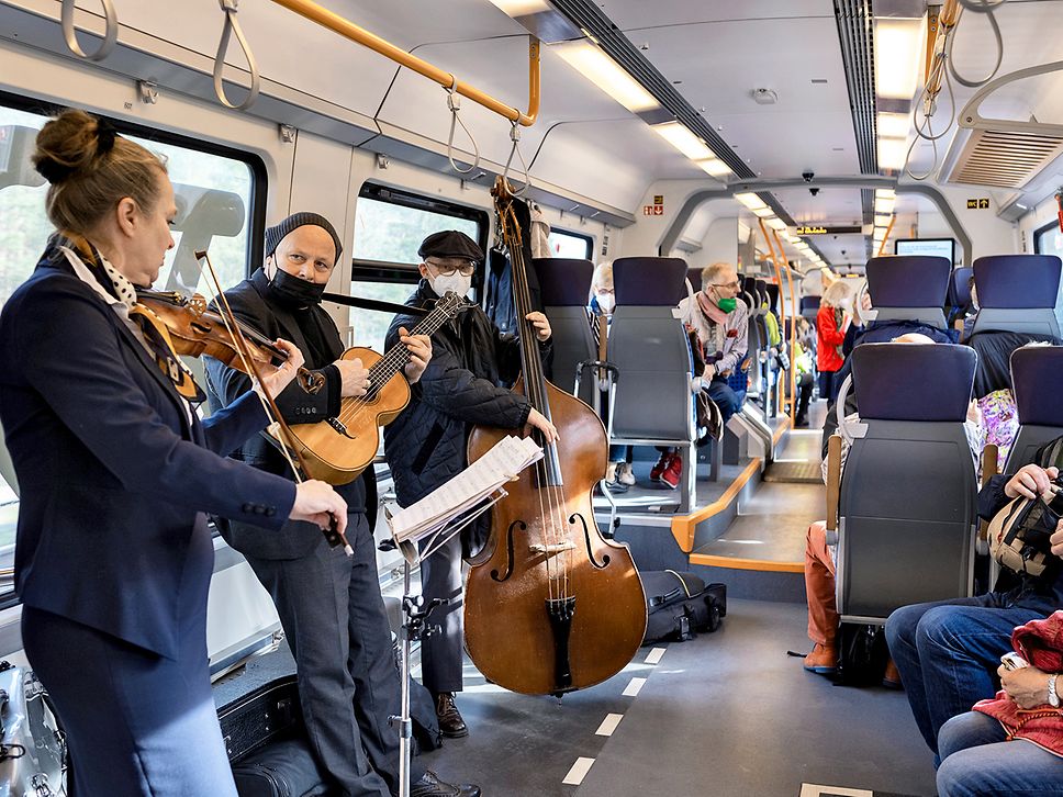 Band bestehend aus Geigerin, Gitarristen und Kontrabassisten spielt im Regionalzug