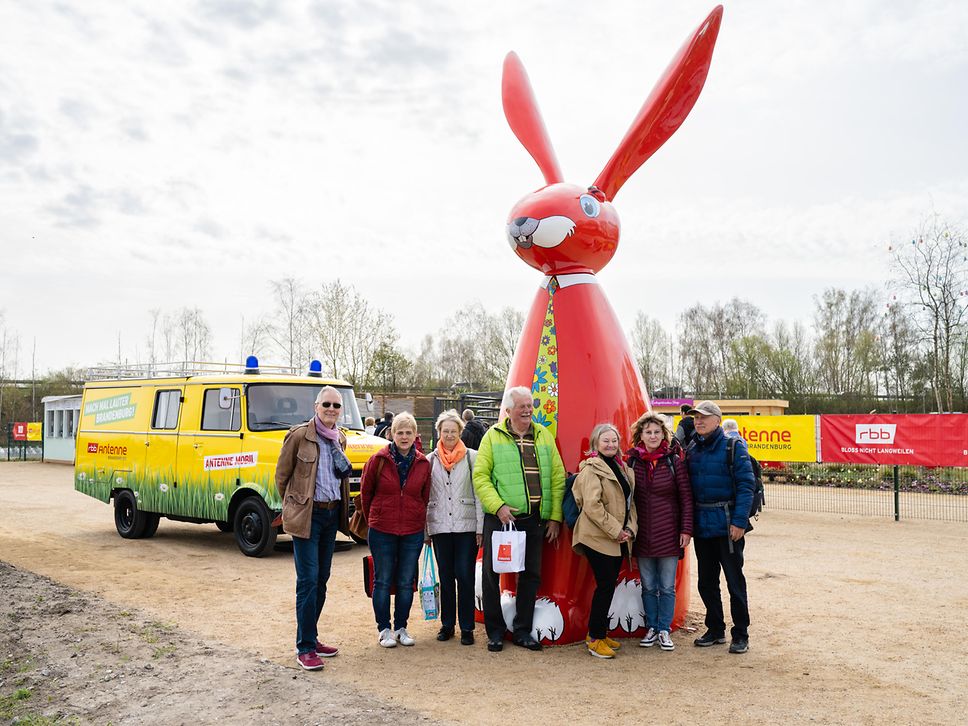 Reisegruppe posiert vor großem roten Osterhasen