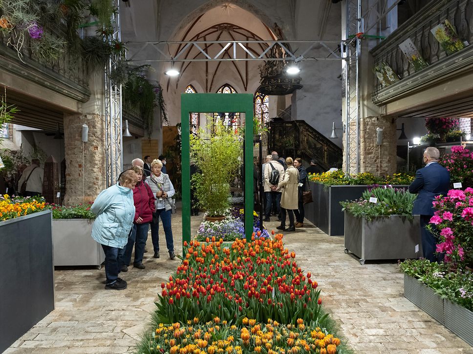 Besucher:innen betrachten Blumenbeete in einer Kirche