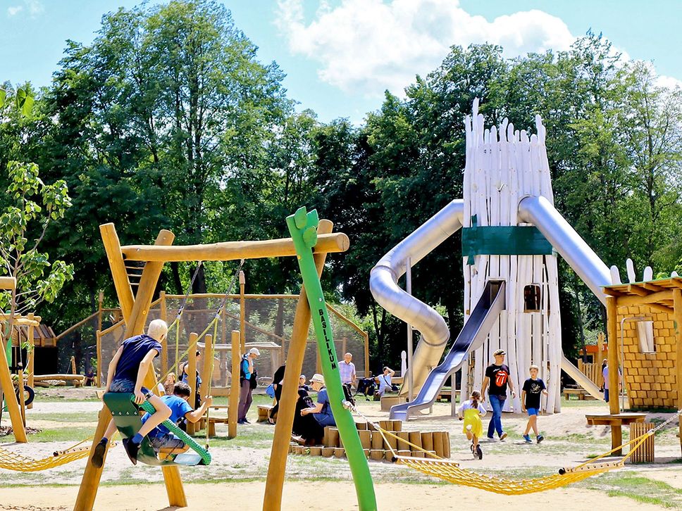 Blick auf den Spielplatz der LAGA Beelitz mit Spielgeräten aus Holz, unter anderem ein Spielturm aus Spargelstangen.